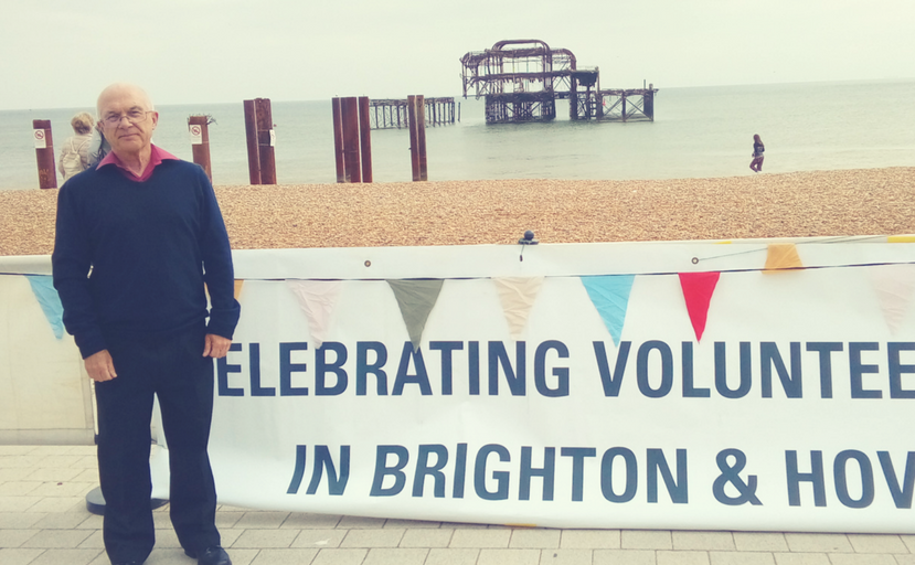 Peter standing with banner reading "Celebrating volunteering in Brighton & Hove"