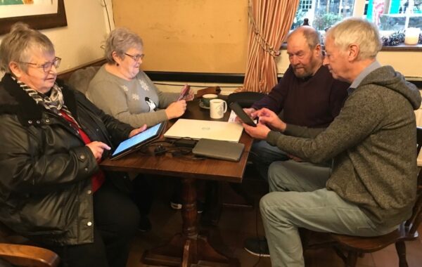People using tablets and phones in a pub.